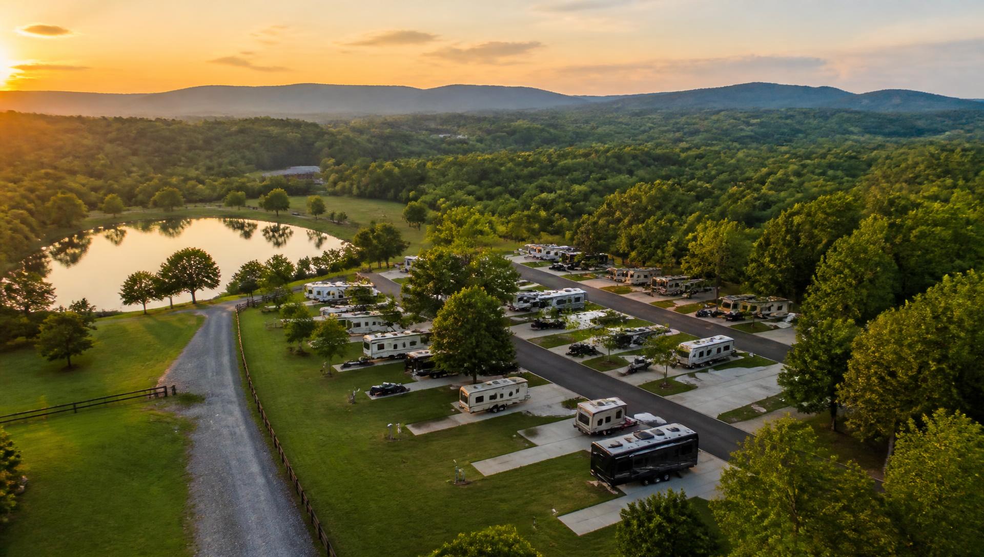 Aerial view of a Tennessee RV park at sunset with paved sites, trees, and a lake
